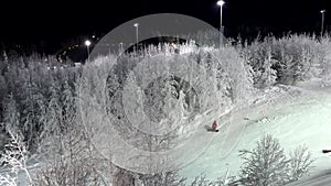 Aerial shot of snowboarder falling down at night. Snowfields and forest in the distance. Doing winter sports