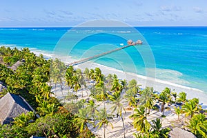 Aerial shot of the Stilt hut with palm thatch roof washed with turquoise Indian ocean waves on the white sand sandbank beach on