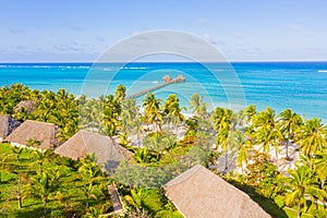 Aerial shot of the Stilt hut with palm thatch roof washed with turquoise Indian ocean waves on the white sand sandbank beach on