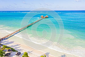 Aerial shot of the Stilt hut with palm thatch roof washed with turquoise Indian ocean waves on the white sand sandbank beach on