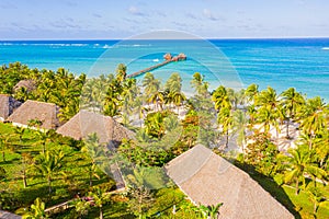 Aerial shot of the Stilt hut with palm thatch roof washed with turquoise Indian ocean waves on the white sand sandbank beach on