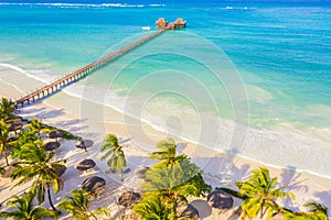 Aerial shot of the Stilt hut with palm thatch roof washed with turquoise Indian ocean waves on the white sand sandbank beach on