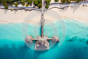 Aerial shot of the Stilt hut with palm thatch roof washed with turquoise Indian ocean waves on the white sand sandbank beach on