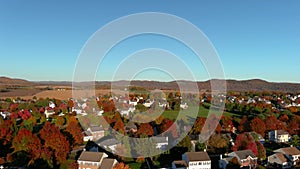 Aerial shot of the suburban neighborhood with houses and colorful trees, drone moving from up to down