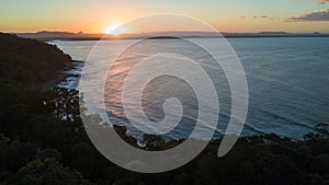 Aerial shot of the sun setting above the coast line around Noosa in the Sunshine cost