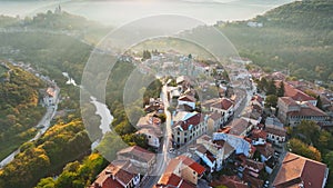 Aerial shot of sunny slightly foggy morning in Veliko Tarnovo, Bulgaria. Flying over old houses, Ascension Cathedral and