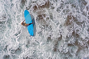 Aerial shot from a surfer going to surf in the ocean