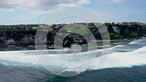 Aerial shot: Surfers in the ocean, male surfer catches and ride a massive barreling waves. Drone tracking footage of a