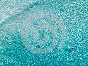 Aerial shot of swimmers on a beautiful beach with blue water and white sand - deep water