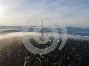 Aerial shot of telecommunication towers on the top of a hill on a foggy day