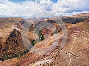 Aerial shot of the textured yellow nad red mountains resembling the surface of Mars