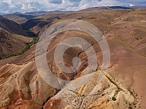 Aerial shot of the textured yellow nad red mountains resembling the surface of Mars