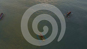 Aerial shot of three fisherman`s boats in a sea at sunset time. Drone moves upwards