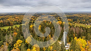 Aerial shot of a tower surrounded by autumn trees in a forest, Haanja, Munamagi, Estonia