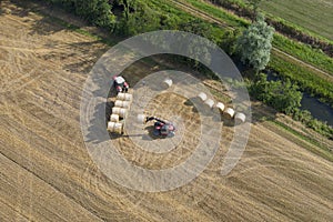 Aerial shot of tractor collecting straw bales