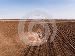 Aerial shot of a tractor cultivating field at spring