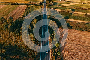 Aerial shot of traffic on countryside road in summer sunset, high angle view drone pov image of cars driving along the highway