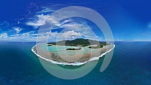 Aerial shot of a tropical island surrounded by crystal-clear blue water.