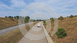 Aerial shot of truck with cargo trailer driving on motorway and transporting goods. Camera following to delivery lorry