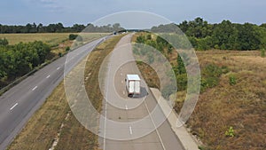 Aerial shot of truck with cargo trailer driving on motorway and transporting goods. Camera following to delivery lorry