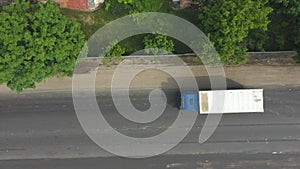 Aerial shot of truck moving on asphalt highway in countryside. Drone flying over lorry transporting cargo along freeway