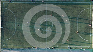 Aerial shot Two teams playing ball in football outdoors, top view. Football game outdoors, green field with markings