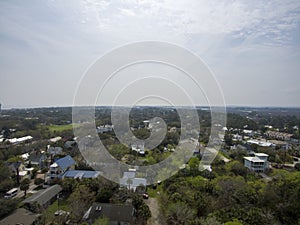 aerial shot of vast miles of homes nestled in between lush green trees with blue sky and clouds in Tybee Island Georgia