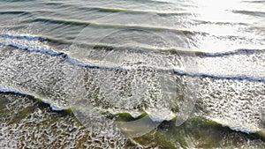 Aerial shot of waves that go to shore crashing on the beach and white water tide in the Pacific Ocean