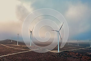 Aerial shot of wind turbines under a cloudy sky.