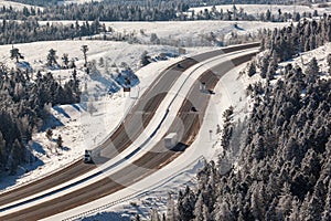 Aerial shot of winter roads lined with snow and alpine trees along I-80 in southern Wyoming