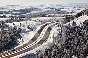 Aerial shot of winter roads lined with snow and alpine trees along I-80 in southern Wyoming