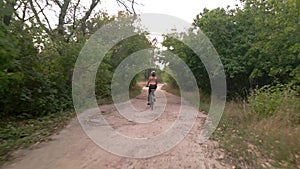 Aerial shot of young sport woman rides bicycle on countryside dusty road at summer evening. Healthy cycling lifestyle