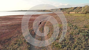 Aerial shot of young sporty woman running outdoor near the lake or liman during beautiful sunrise or sunset