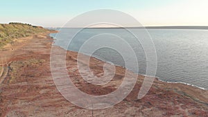 Aerial shot of young sporty woman running outdoor near the lake or liman during beautiful sunrise or sunset