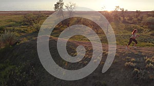 Aerial shot of young sporty woman running outdoor near the lake or liman during beautiful sunrise or sunset