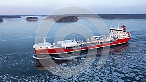 Aerial side view of LNG powered oil and chemical tanker making way ahead in Finnish archipelago during winter