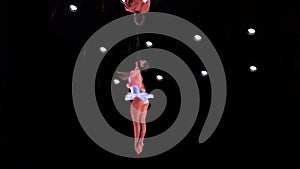 Aerial silk duo of circus artist with white costume on black stage background performing fast spinning trick