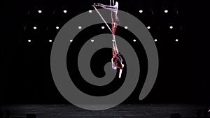 Aerial silk duo in white costumes on black background performing. Concept of desire, attraction and relationship