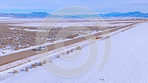 AERIAL: Silver SUV drives along a scenic interstate crossing snowy Montana.