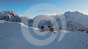 Aerial: ski lift, houses, cafe on top of the mountain in Dombay in winter