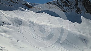 Aerial: a skier goes down the slope on fresh snow in huge mountains