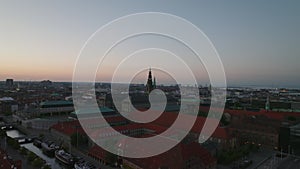 Aerial slide and pan footage of Christiansborg palace with tall tower against colourful twilight sky. Copenhagen