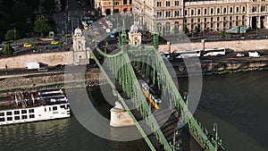 Aerial slide and pan shot of end of old Szabadsag bridge and trams passing over it at golden hour. Budapest, Hungary