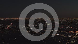 AERIAL: Slow flight over Hollywood Hills at Night with view on Downtown Los Angeles Skyline