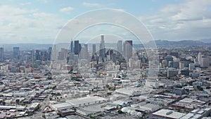 AERIAL: Slow Side Shot of Downtown Los Angeles Skyline with Warehouse Art Distrct in Foreground with Blue Sky and Clouds