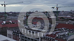 AERIAL: Slowly flying over Center of Berlin Germany with Construction Site Cranes at Sunset