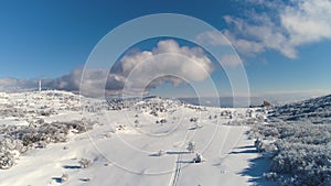 Aerial for the snowy countyside road with forest and fields surrounding. Shot. Rural winter area with road in winter