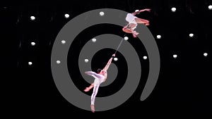 Aerial straps duo with white costume on black stage background doing performance