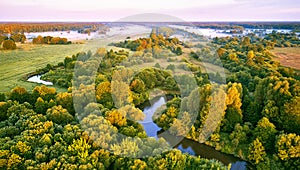 Aerial summer sunrise view. Rural landscape, river meandering in forest green trees. Morning Misty Scene. Serene atmosphere fog