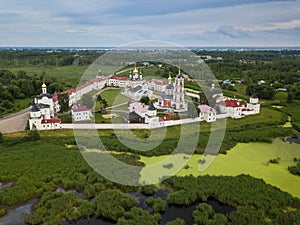 Aerial summer view of white old monastery with golden domes among green fields in Rostov the Great city. Russia